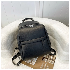 Gros plan sur la texture du cuir grainé noir et les doubles zips argentés du sac à dos
