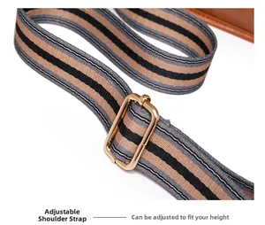 Détail de la bandoulière rayée réglable avec boucle dorée sur un sac à main marron