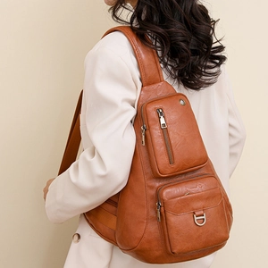Close-up of brown vintage leather crossbody bag featuring multiple zipper pockets and metal D-ring
