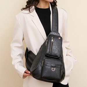 Detail of a vintage black crossbody bag with functional zippers and a metal D-ring buckle
