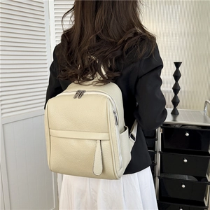 Détail du sac à dos en cuir PU blanc cassé avec texture litchi, poche latérale et plis