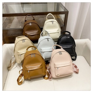 Collection of colorful pebbled PU leather mini backpacks in a cozy home interior setting