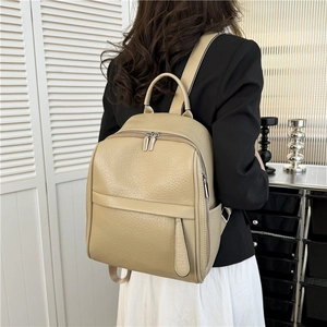 Vue détaillée d'un sac à dos en cuir beige texturé porté par un mannequin en intérieur