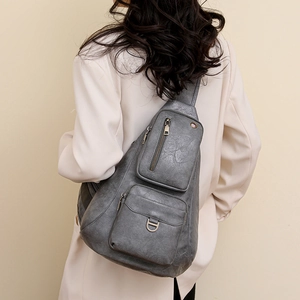 Detail of vintage grey leather crossbody bag showing textured finish and metal hardware