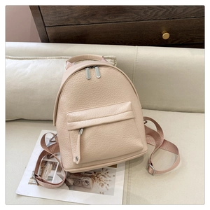 Detailed macro view of the light pink pebble leather texture and silver zipper of the backpack