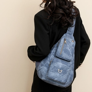 Detail view of the blue denim crossbody bag featuring multiple zipper pockets and D-ring buckle