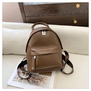 Detail of the brown textured faux leather backpack showing the front pocket and main zipper