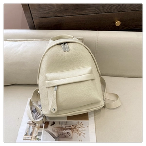 Detail of cream faux leather backpack with lychee texture and metallic zippers