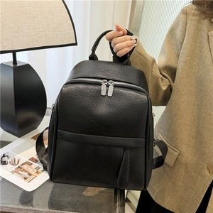 Détail d'un sac à dos noir en cuir texturé avec zips argentés et poignée haute