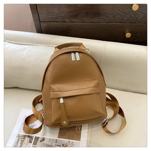 Side view of soft light brown PU leather backpack with silver hardware in home setting