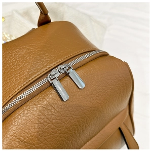 Détail d'un sac à dos vintage en cuir marron avec doubles fermetures éclair en métal