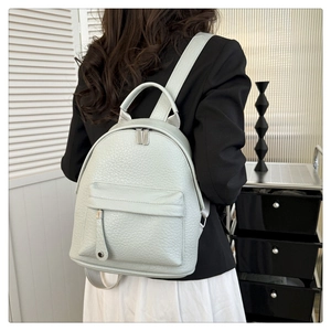Rear view of a model wearing a mint green faux leather backpack in a modern indoor setting