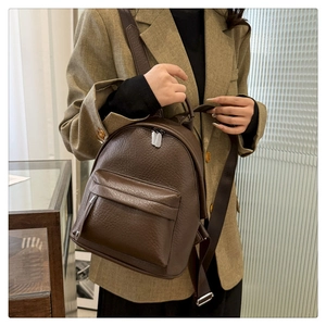 Detail of dark brown pebble leather mini backpack with silver metal zippers and front pocket