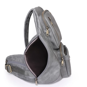 Detailed close-up of grey vintage leather chest bag showing metallic zippers and texture
