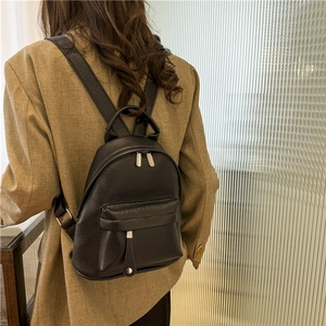 Detailed view of women's black leather backpack with lychee grain texture and metal zippers
