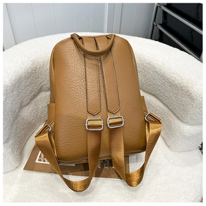 Vue détaillée d'un sac à dos en cuir marron avec bretelles réglables sur chaise blanche