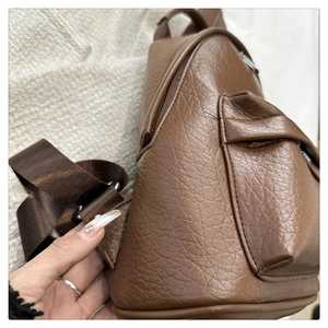 Side view of brown lychee-patterned PU leather backpack with a front flap pocket