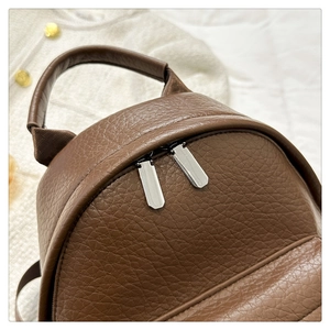 Detail of brown litchi pattern leather backpack with padded handle and metal zippers