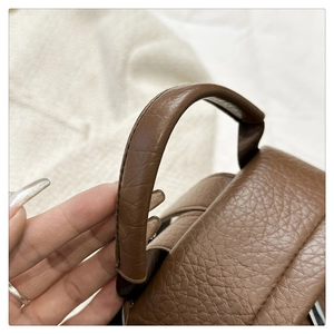 Detailed close-up of brown litchi pattern PU leather top handle with sturdy stitching