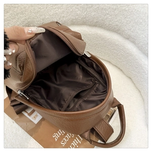 Internal view of brown PU leather backpack showing zip pocket and textile lining