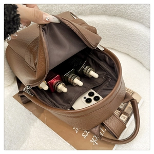 Brown PU leather backpack interior storage with phone and cosmetics on white background