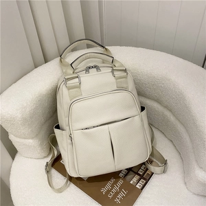 Detail of creamy white pebble leather backpack featuring multiple functional front zippers