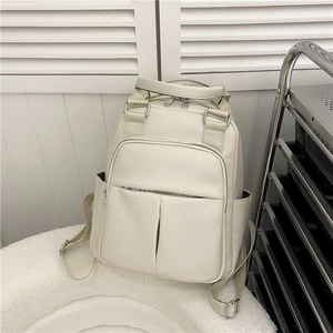 Detailed macro view of the cream-colored pebbled leather texture and silver zippers on backpack