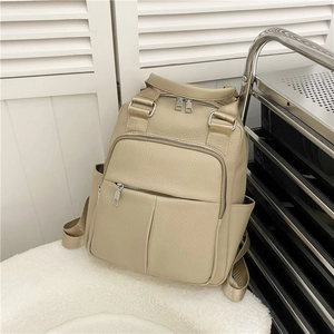 Detail of beige faux leather backpack texture with zippers on white plush surface
