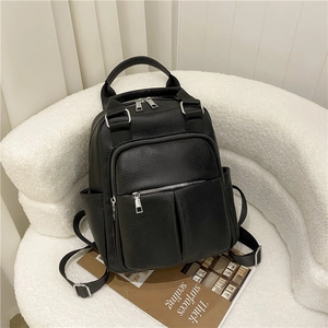 Detail of black pebbled leather backpack with silver zippers and side pockets