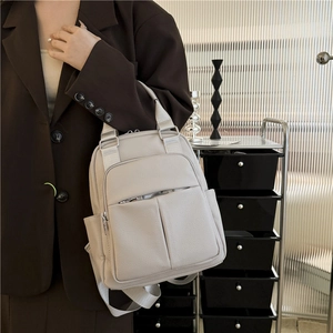 Close-up of cream PU leather backpack with lychee grain texture and silver zippers