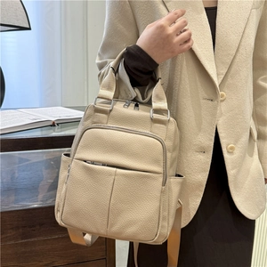 Close-up of beige lychee grain PU leather backpack with silver zippers and side pocket