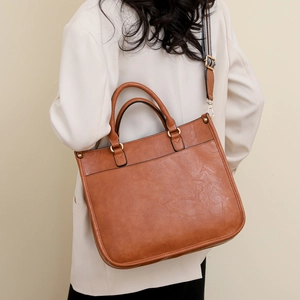 Brown faux leather vintage tote bag with striped shoulder strap shown on model back