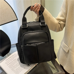 Close-up of black litchi pattern leather backpack with silver metal zippers and pocket