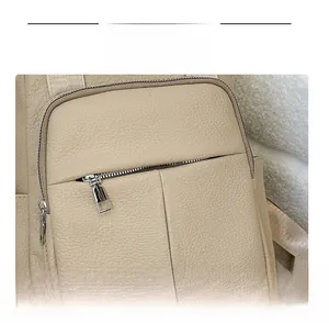 Detail of beige faux leather backpack showing pebbled texture and silver metal zipper