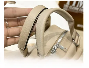 Close-up of comfortable reinforced handle and durable metal zippers on beige backpack