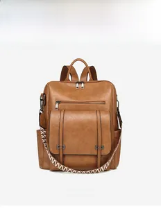 Front detail of brown PU leather backpack with geometric woven strap and zip pockets