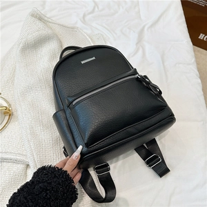 Detail view of black PU leather backpack with lychee texture and silver metal brand plate