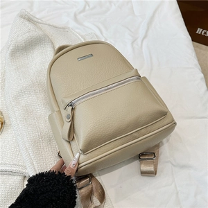 Detail of beige litchi grain leather backpack with silver zippers and webbing straps