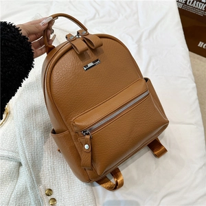 Close-up of brown pebble grain leather backpack with silver hardware and front zipper pocket