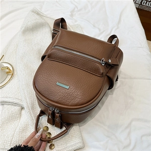 Detail of dark brown faux leather backpack featuring pebble texture and front zip pocket