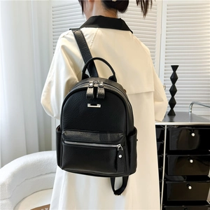 Rear view of a stylish black PU leather backpack worn by a model in a modern room