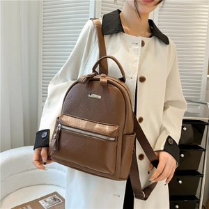 Detail view of brown pebbled PU leather backpack with front zipper pocket and metal accent