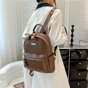 Close-up of brown PU leather backpack with lychee texture and silver metal nameplate