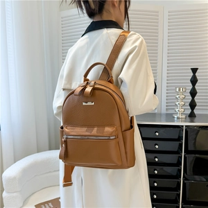 Brown faux leather backpack detail showing lychee texture and side pocket on white coat