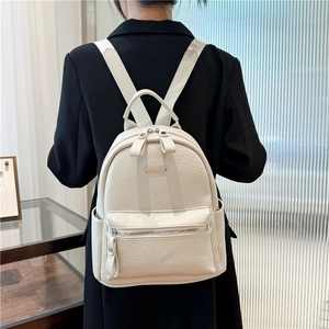 Detail view of cream white pebbled PU leather backpack with silver zippers and side pocket