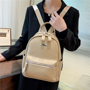 Detail of beige pebble leather backpack with silver zippers and wide straps