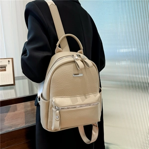Business casual beige leather backpack shown from a side view on a model in a suit
