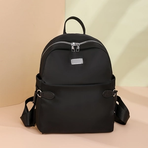 Detail eines wasserdichten schwarzen Oxford-Rucksacks mit silbernen Reißverschlüssen und Seitentaschen