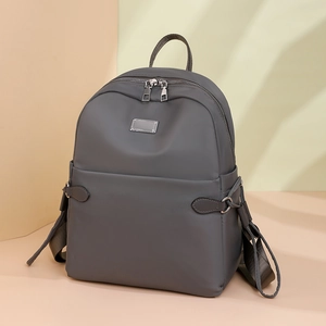 Detailaufnahme des dunkelgrauen Oxford-Rucksacks mit Metallemblem und Reißverschluss