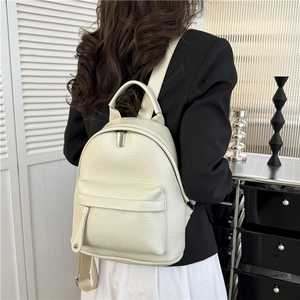 Minimalist ivory faux leather backpack with litchi texture on a female model
